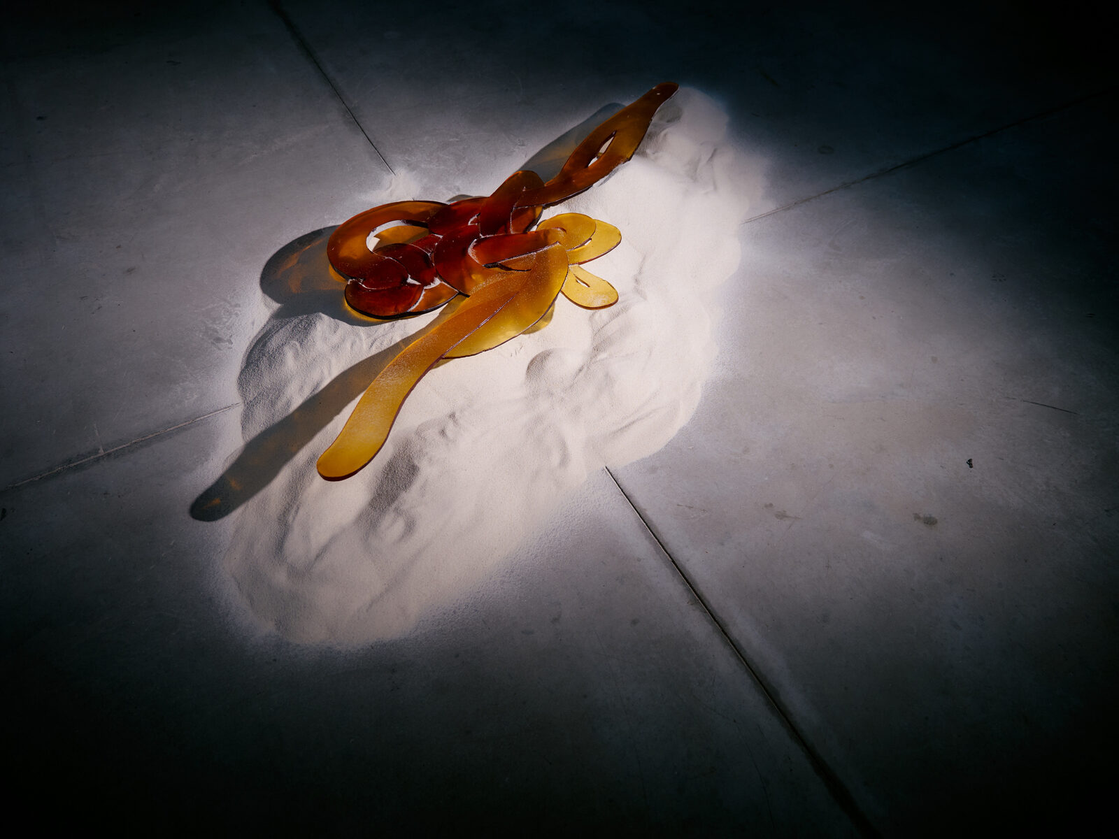 Amber glass form grounded in sand, Illusion installation